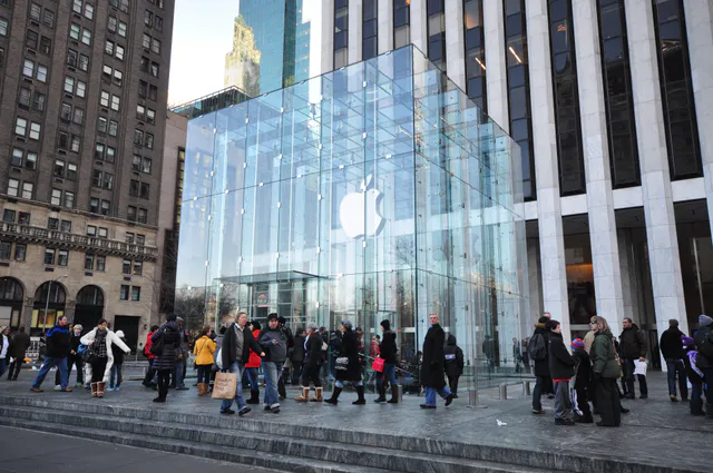 The glass-cube entrance of Apple's Fifth Avenue retail store in New York City, with the white Apple logo suspended inside the illuminated transparent cube.