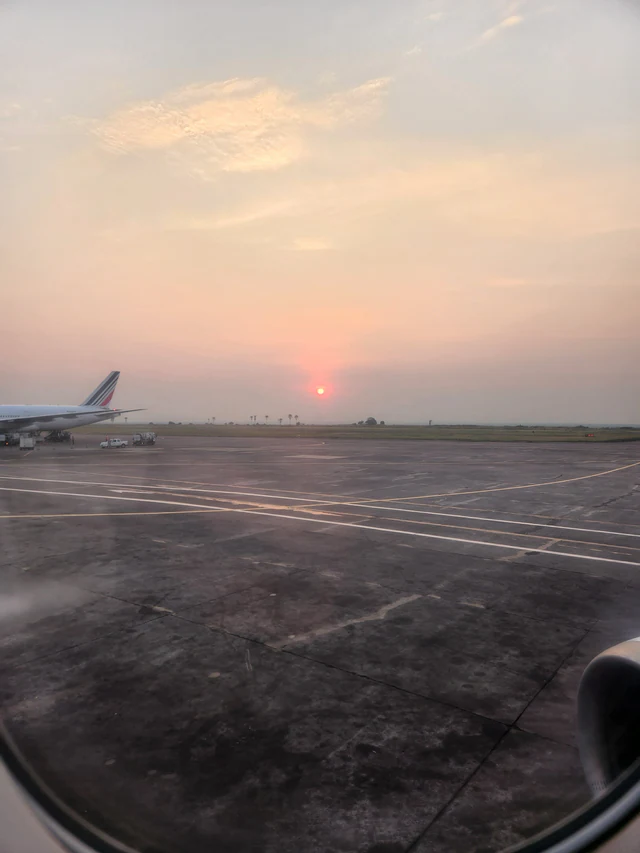 Exterior of N’djili International Airport in Kinshasa, with the airport name above the terminal entrance and an open forecourt.