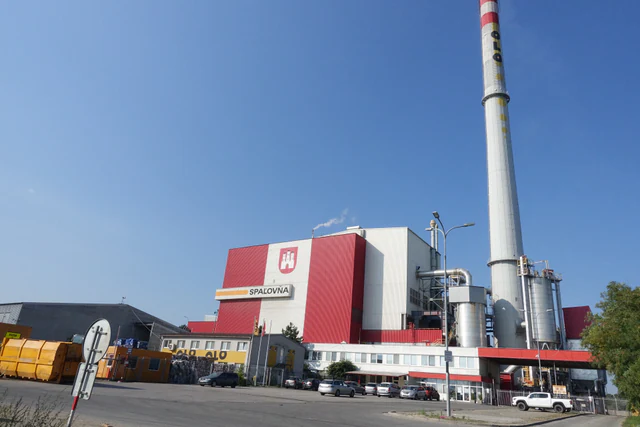 Aerial view of a municipal waste incineration plant in Bratislava, with industrial buildings and two tall chimneys.