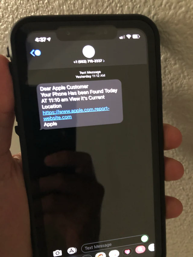 Close-up photograph of a smartphone displaying a phishing text message linking to a fake login portal.