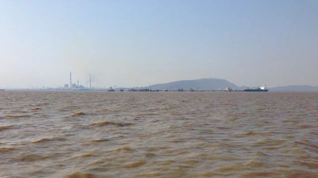 Oil refinery towers and a tanker viewed across Mumbai harbor in India