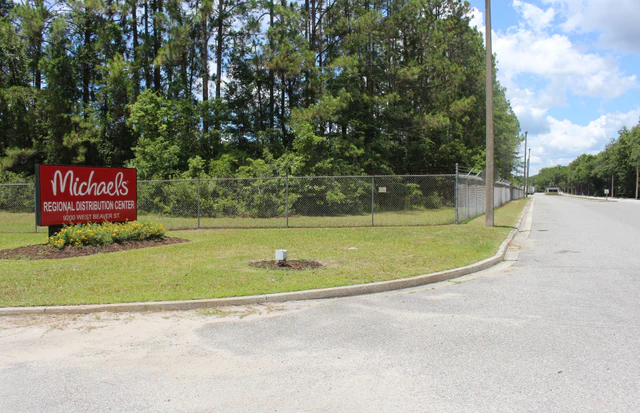 Long, low-rise Michaels distribution warehouse behind a fence in Jacksonville, Florida.