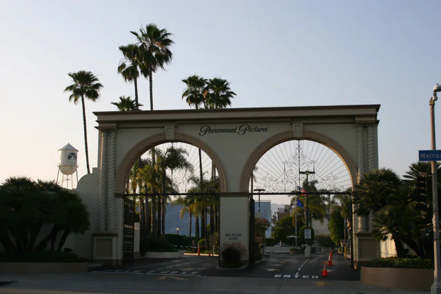 The ornate arched Melrose Gate entrance to Paramount Pictures Studios against a clear sky.