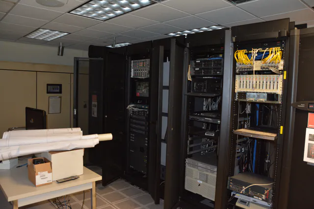 Rows of illuminated server racks running down a long aisle inside a data center hall.