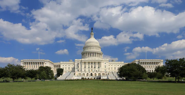 Wide view of the west front of the United States Capitol building under a blue sky
